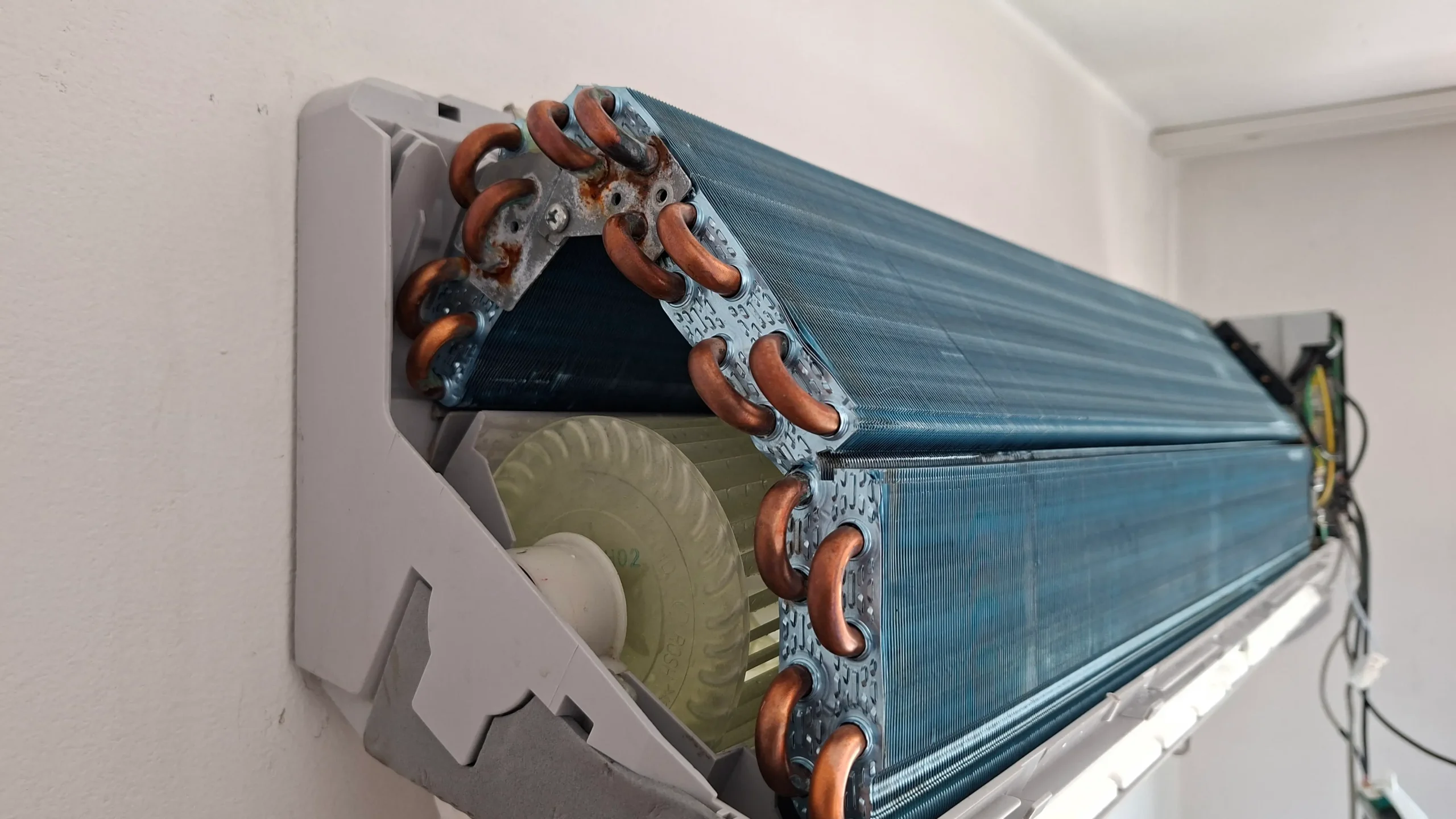 разглобено вътрешно тяло на климатик с видима турбина и топлообменник